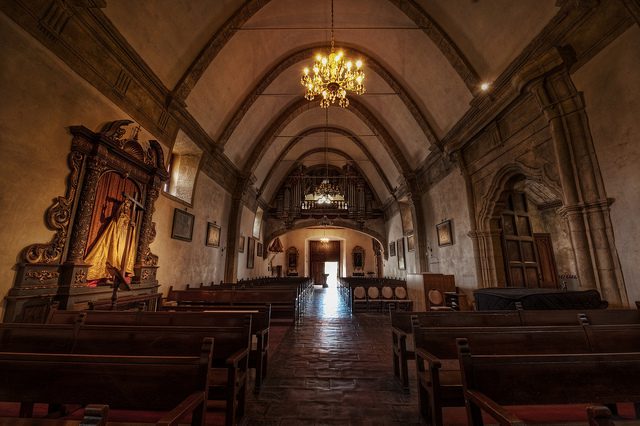 The inside of a church with wooden pews and a chandelier.