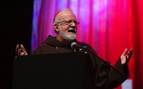 A man in a monk's robe speaking into a microphone.