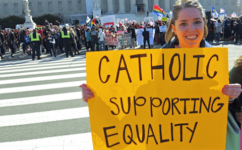 A woman holding a sign that says catholic supporting equality.