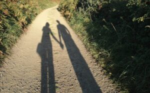 The shadow of a couple holding hands on a path.