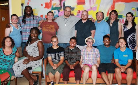 A group of people posing for a photo in front of a painting.