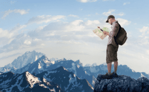 A man standing on top of a mountain looking at a map.