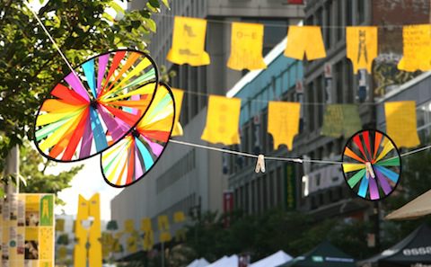 Colorful spinners hanging from a tree in a city.