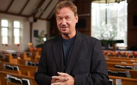 A man in a black suit standing in a church.