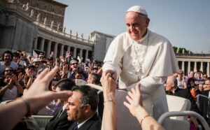 Pope francis shakes hands with a crowd of people.