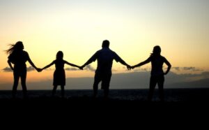 Silhouette of a family holding hands at sunset.