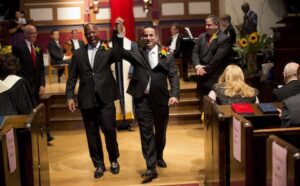 Two men in tuxedos walking down the aisle.