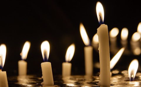 A group of candles lit in a dark room.