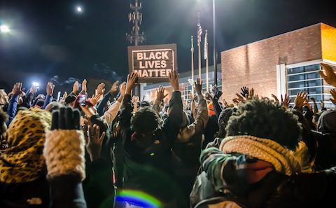 A group of people holding up signs at night.