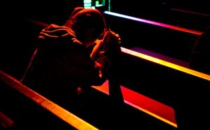 A woman praying in a dark church.