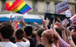 A group of people waving rainbow flags in a crowd.