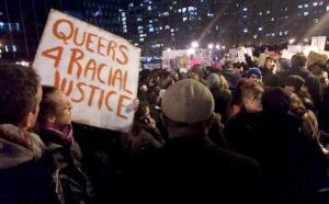 A group of people holding a sign that says queers for racial justice.