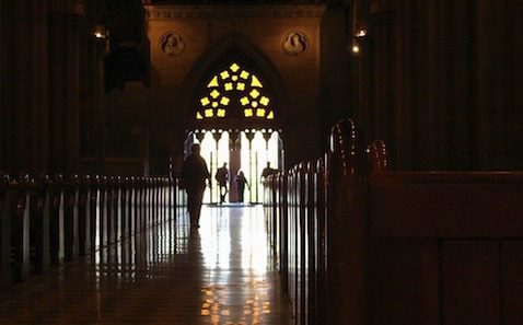 A person is walking down the aisle of a cathedral.