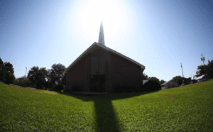 A church with a cross in the grass.