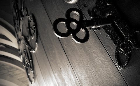 A black and white photograph of a key on a wooden door.