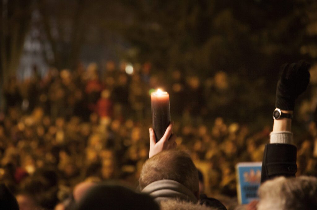 A person holding a candle in front of a crowd.