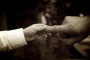 A black and white photo of a man holding a child's hand.