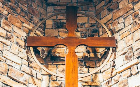 A wooden cross sits on top of a stone wall.