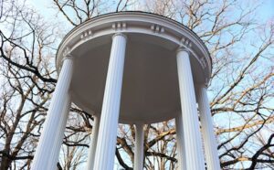 A white pillared structure with trees in the background.