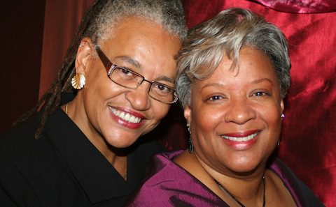 Two women with dreadlocks smiling for the camera.