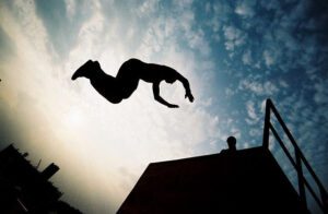 A man jumping in the air over a railing.