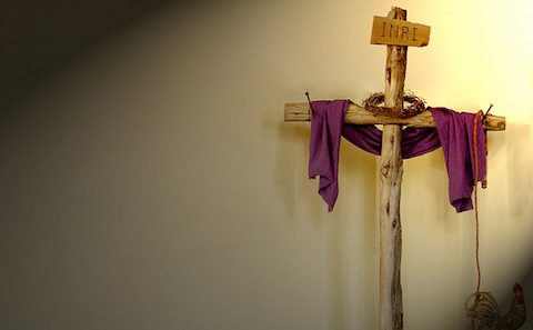 A wooden cross with a purple cloth hanging on it.