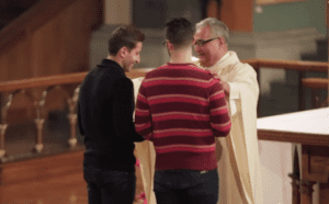 Two men standing next to a priest in a church.