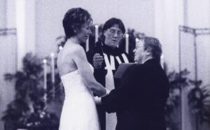 A bride and groom exchange vows in front of a priest.