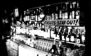 A black and white photo of a bar with many bottles.