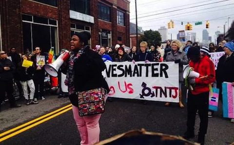 A woman is holding a sign in front of a crowd of people.