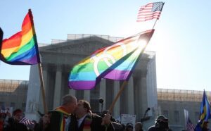Two gay men holding rainbow flags in front of the supreme court.