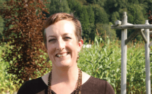 A woman smiling in front of a corn field.