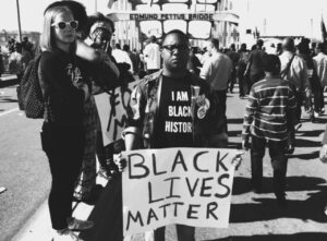 A black man holding a sign that says black lives matter.