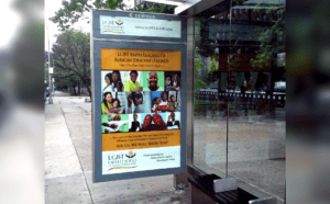 A bus stop with a poster of a group of people.