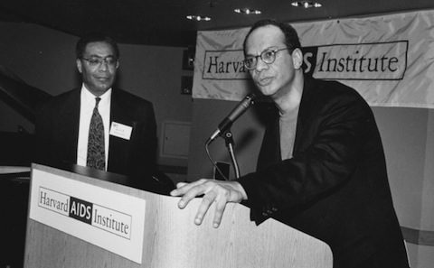 Two men standing at a podium in front of a sign.