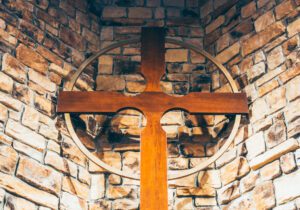 A wooden cross sits on top of a stone wall.