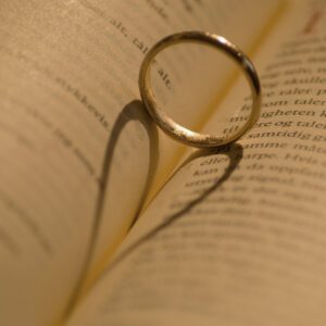 A wedding ring sits on top of an open book.