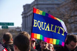 A group of people holding a rainbow flag with the word equality.