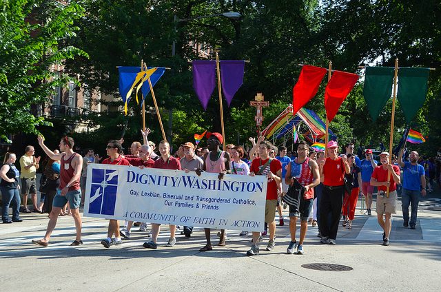 A group of people walking down a street with a banner.