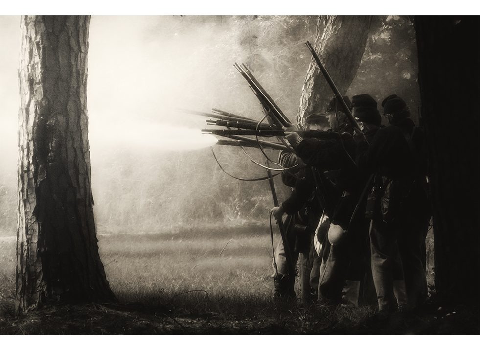 A black and white photo of a group of soldiers in the woods.