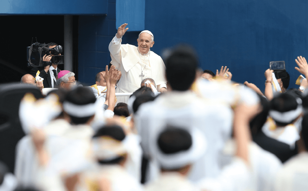 Pope francis waves to a crowd of people.