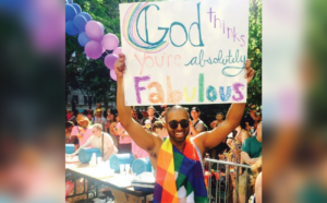 A man holding up a sign that says god you are absolutely fabulous.