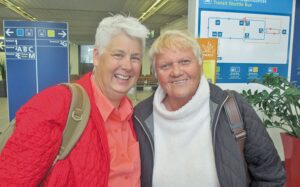 Two older women standing next to each other in an airport.