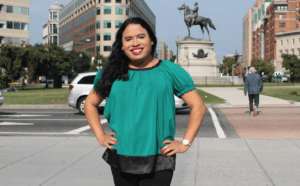 A woman in a green top standing in front of a statue.