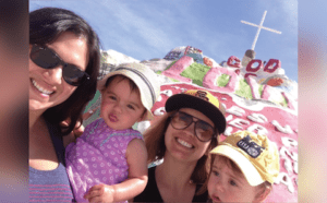 A woman and her two children are posing in front of a cross.