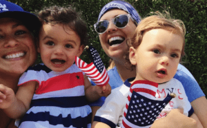 A woman and two children are holding american flags.