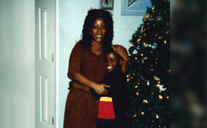 A woman with a child in front of a christmas tree.