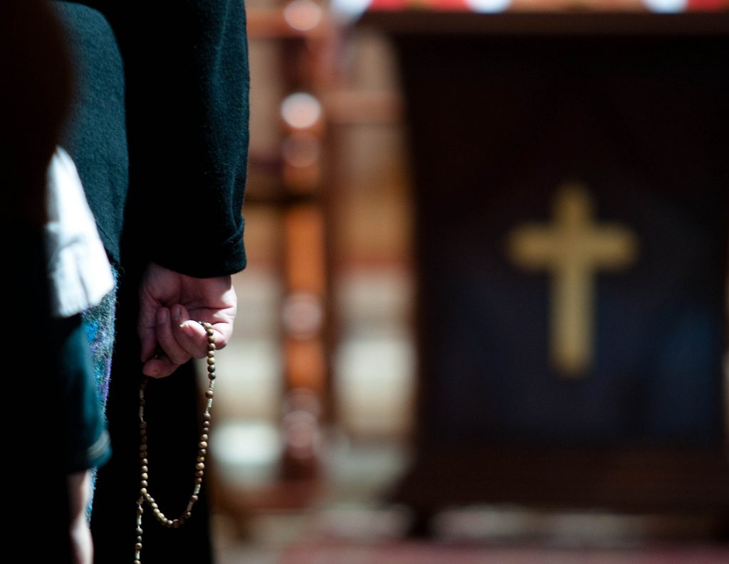 A close up of a person's hand holding a rosary.