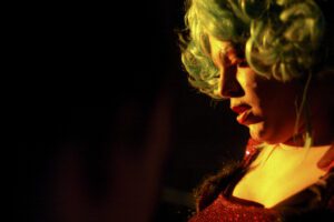 A woman with a green wig in a dark room.
