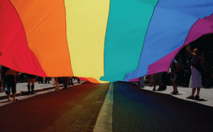 A large rainbow flag is being held by a group of people.